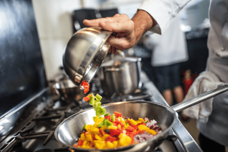 chef pouring sliced vegetables into pan on stove 2022 03 04 01 50 03 utc 1